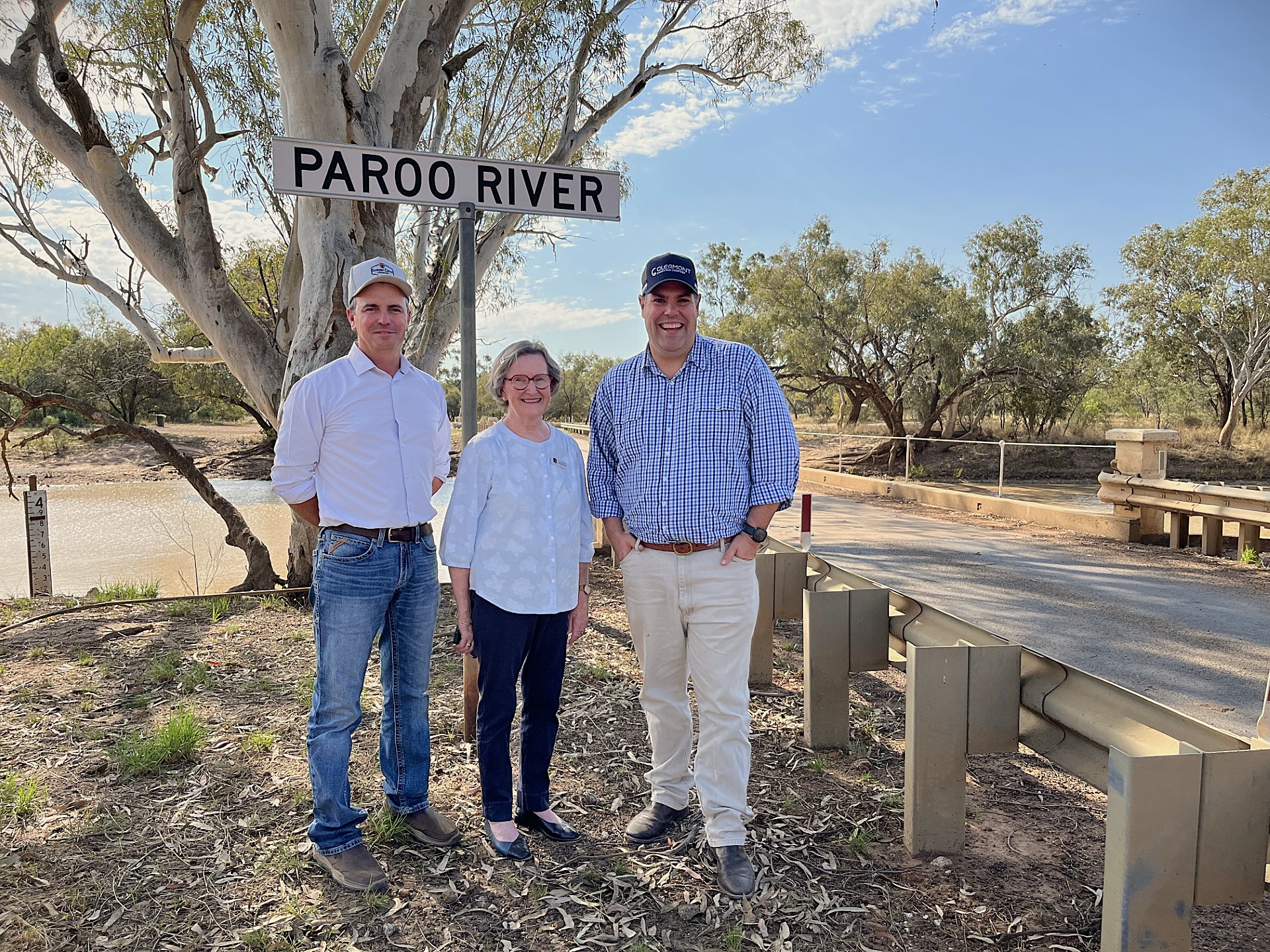 two men and a lady standing near a bridge and a sign saying Paroo River